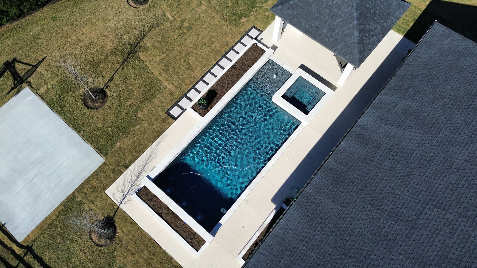 Aerial view of a rectangular pool with dark finish and raised spa