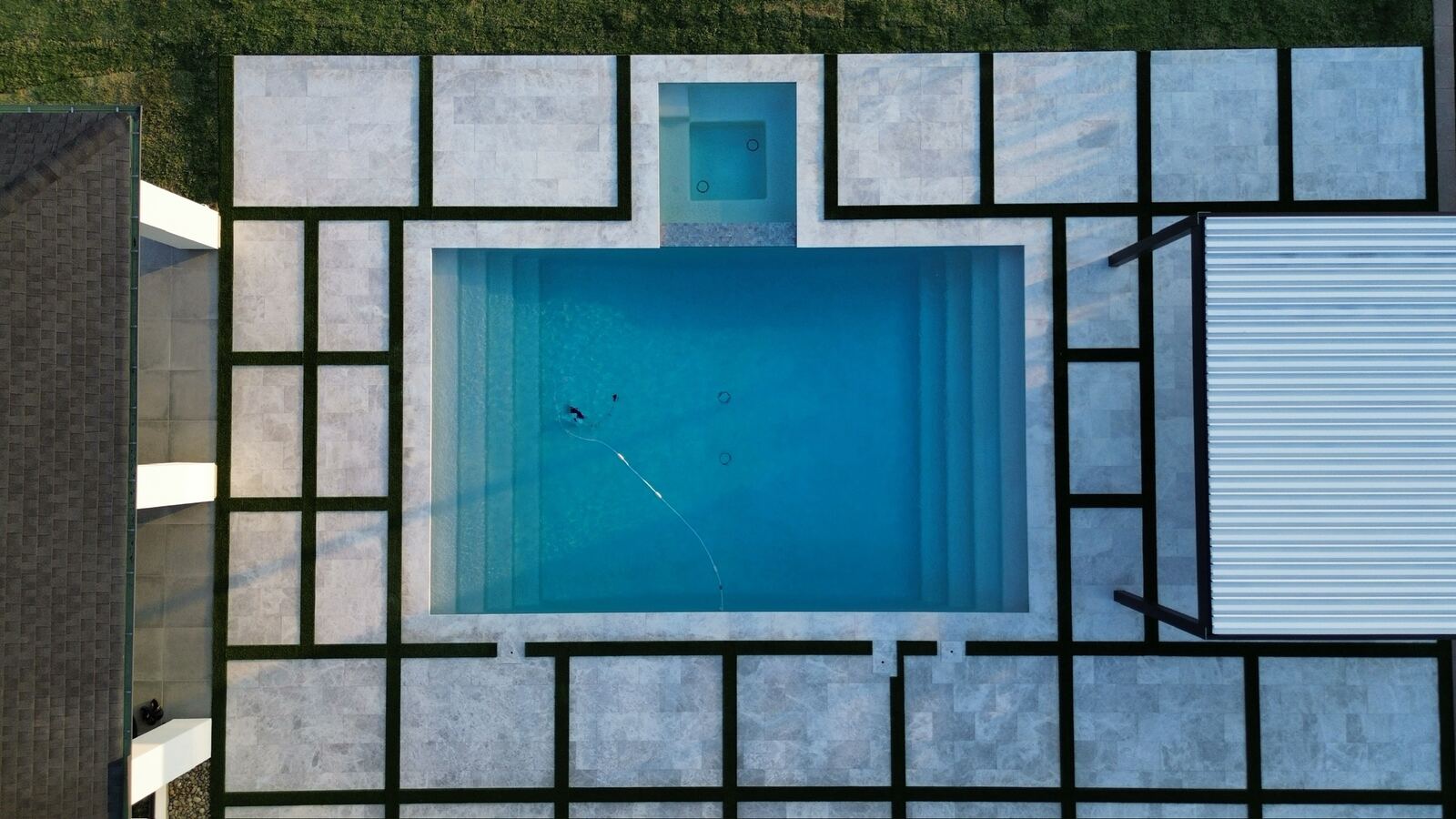 Aerial view of a geometric pool with tiled patio pattern