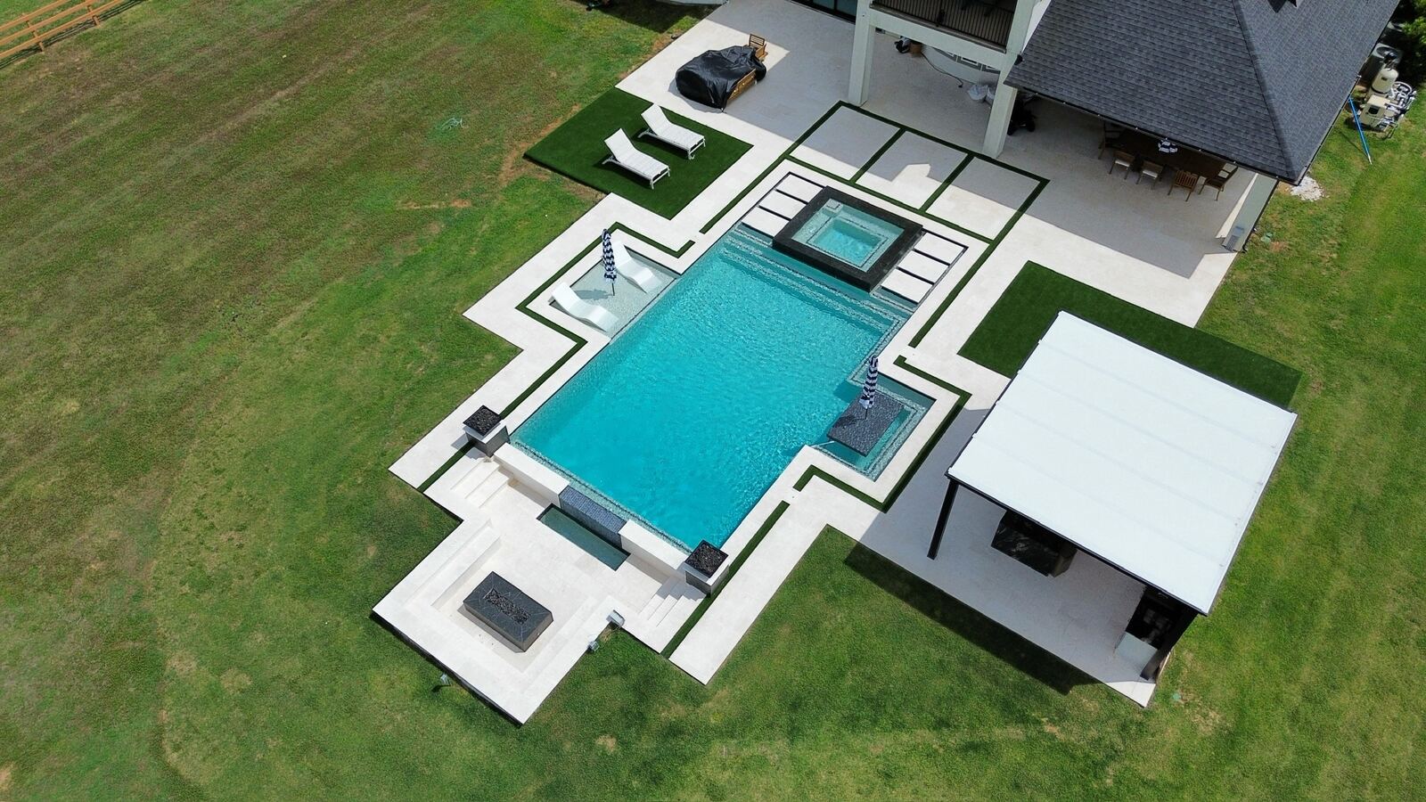 Aerial view of a modern white-deck pool with black accents