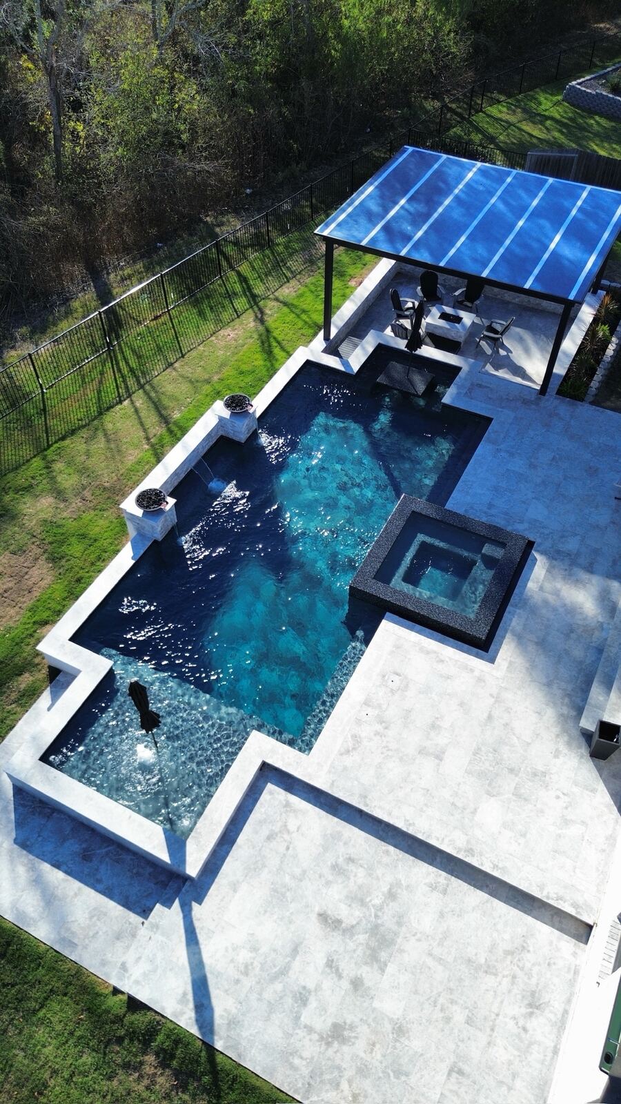 Aerial view of a modern cross-shaped pool with spa and lounge areas