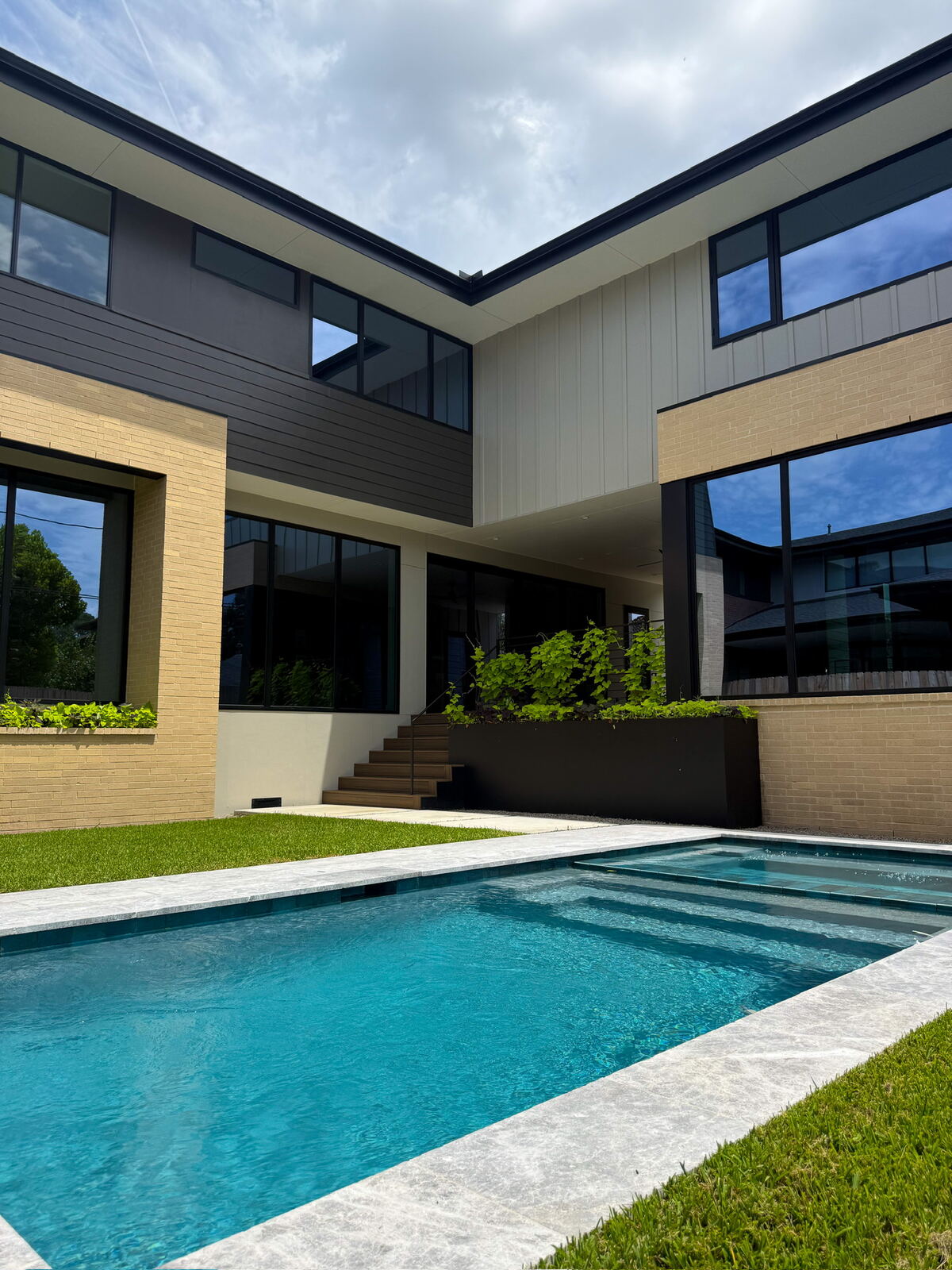Poolside view of a modern pool with sun-shelf steps at dusk