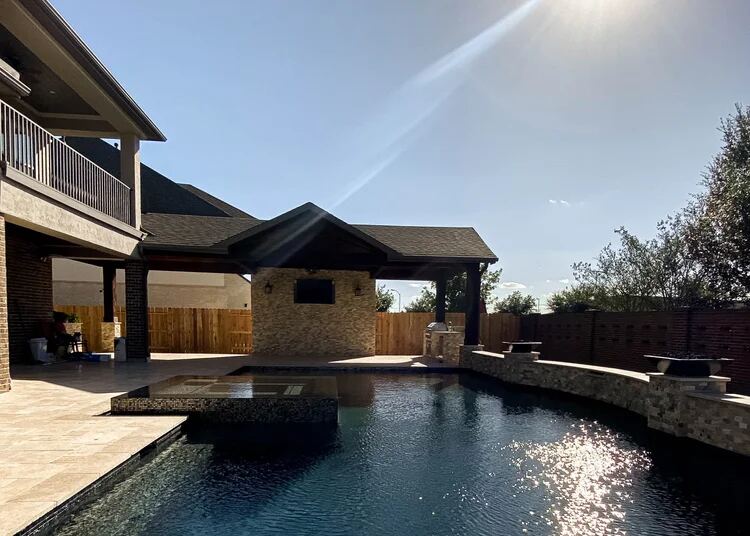 Dark-finish pool beside a covered outdoor kitchen and balcony