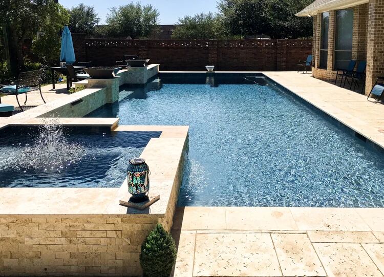 Blue-tile pool with raised spa fountain and travertine deck