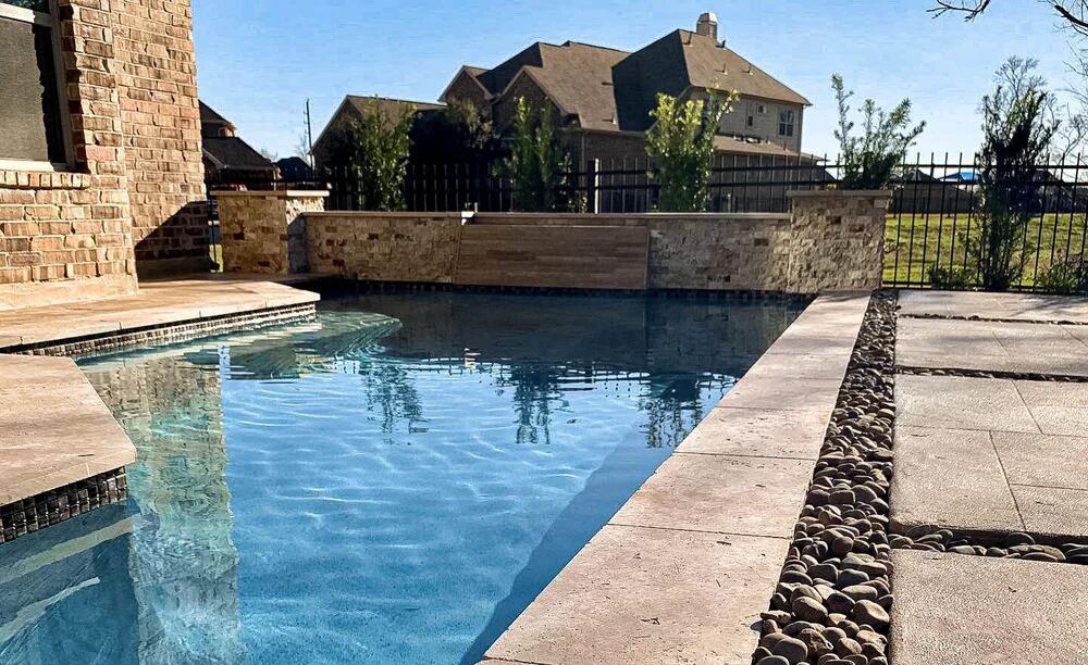 Pool corner with stacked-stone wall, palm trees and iron fence