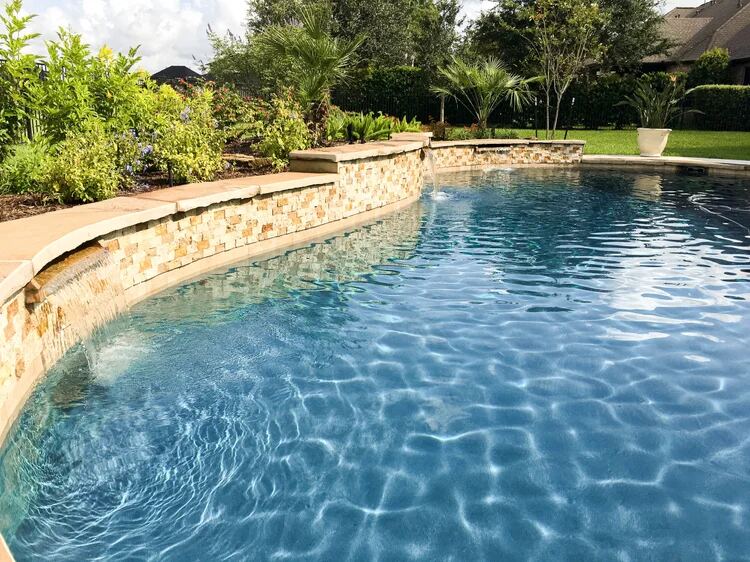Curved stone wall waterfall spilling into the pool