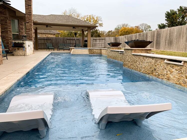 Pool with covered patio, fire bowls and in-water tanning ledge loungers