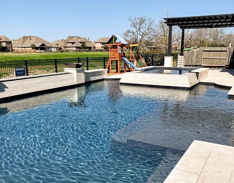 Curved stone wall spillway surrounded by lush landscaping