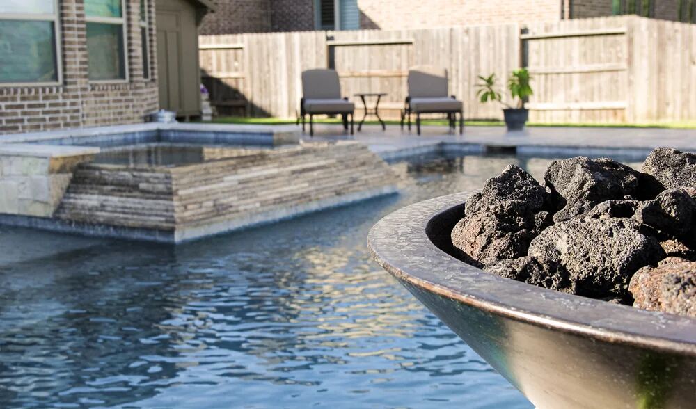 Close-up of a lava-rock fire bowl beside the pool