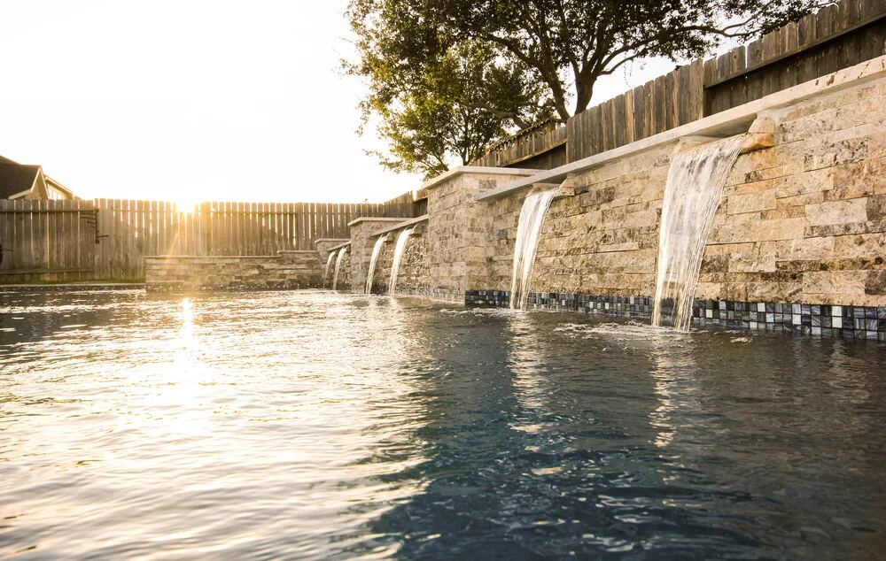 Stone wall with multiple waterfall spillways at sunset