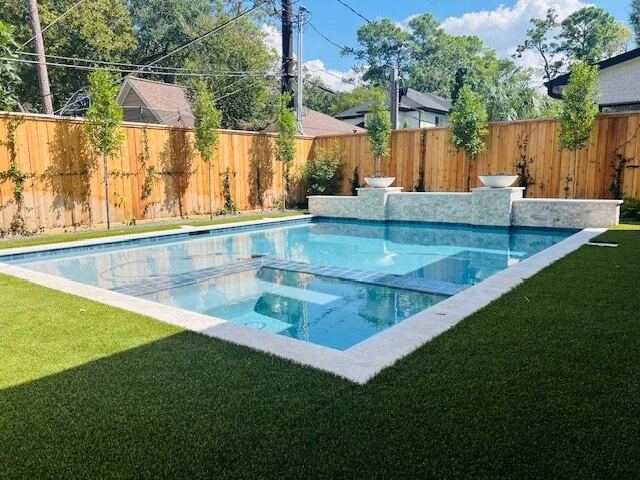 Pool with artificial turf surround and a raised fountain wall