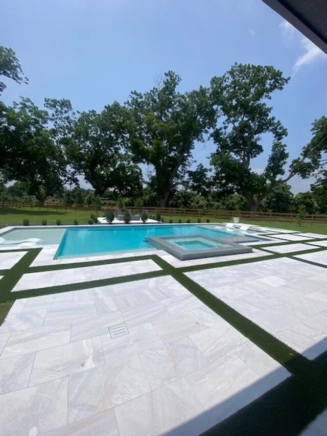 Modern pool with raised spa and marble tile patio